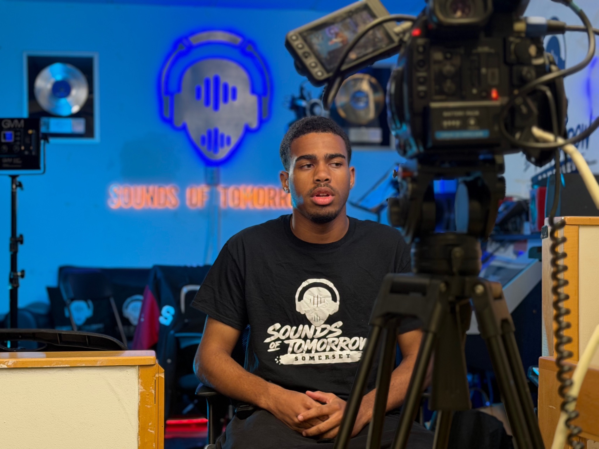 A person in a Sounds of Tomorrow T-shirt during a filmed studio interview